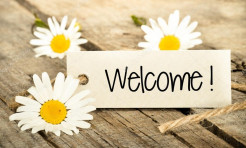 Photo: Three daisy flowers with "Welcome!" on a rectangular piece of paper.