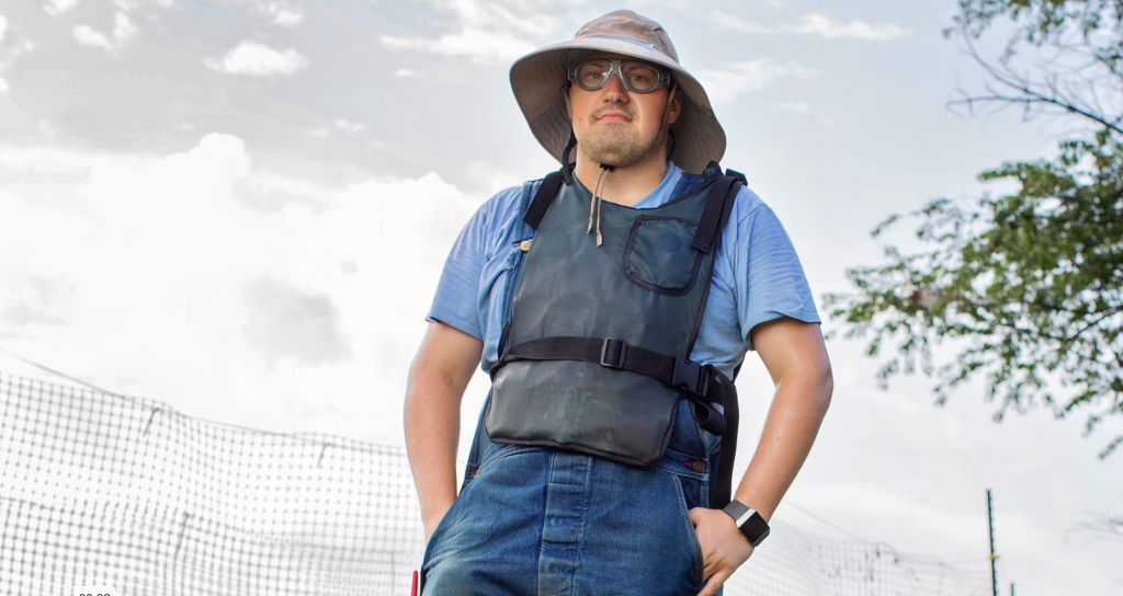 Male worker standing proudly with goggled and work vest in front of a deer fence