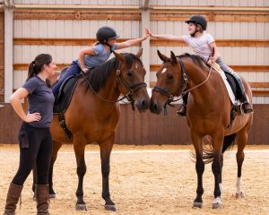 Kids on horses high-fiving each other
