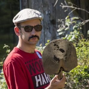 Man wearing sunglasses and hat holding shovel