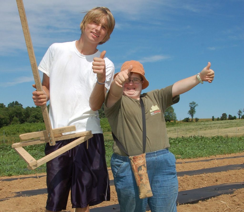 two people standing proudly in the field with a marker tool