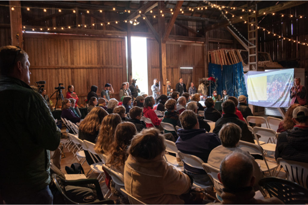 people in a barn listening to a speaker